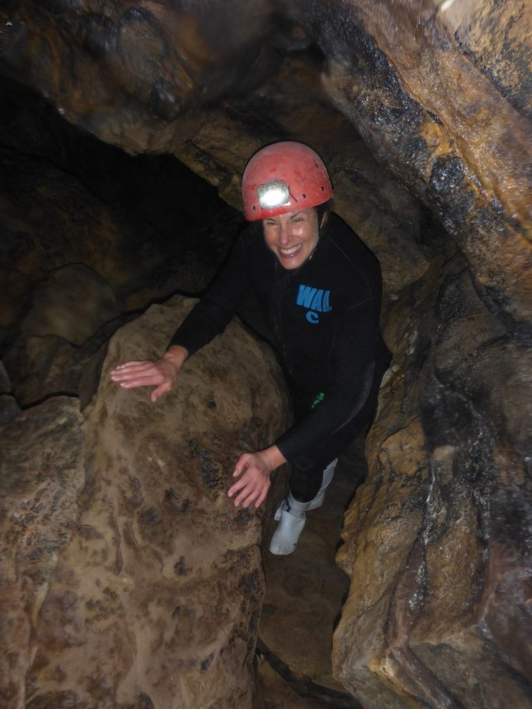Photo: Dr. Beth Karlan, wearing a helmet with reflector, climbing in a cave